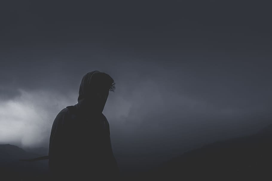 man looking forward on cloudy path, silhouette of man standing during black clouds