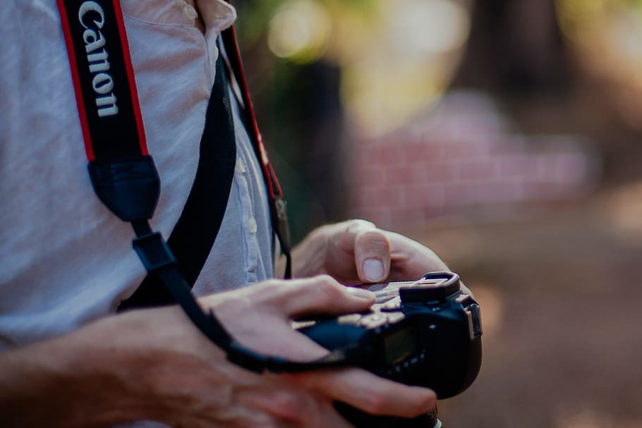 person holding black Canon DSLR camera, person holding black Canon DSLR camera shallow focus photography HD wallpaper