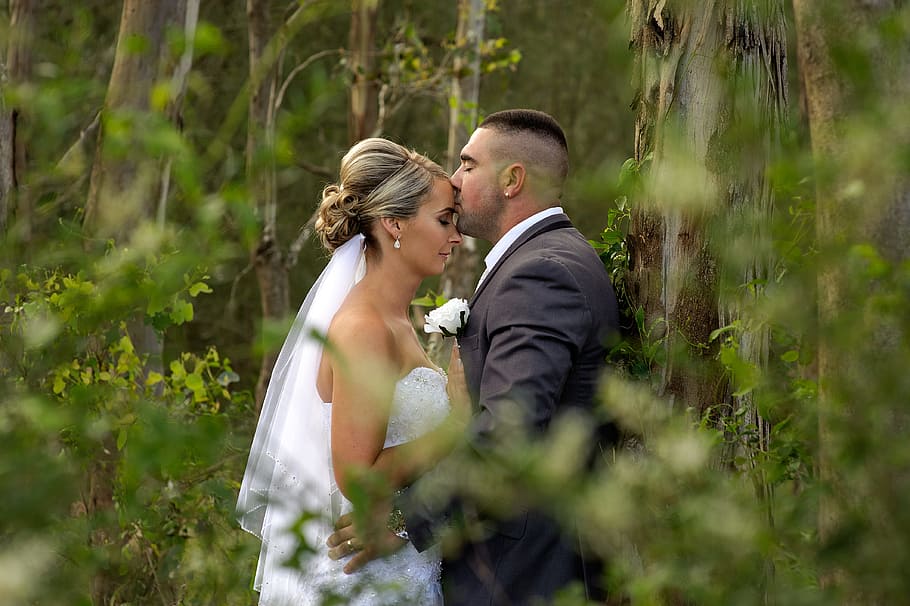 kissing groom and bride during daytime, woman in white strapless wedding dress