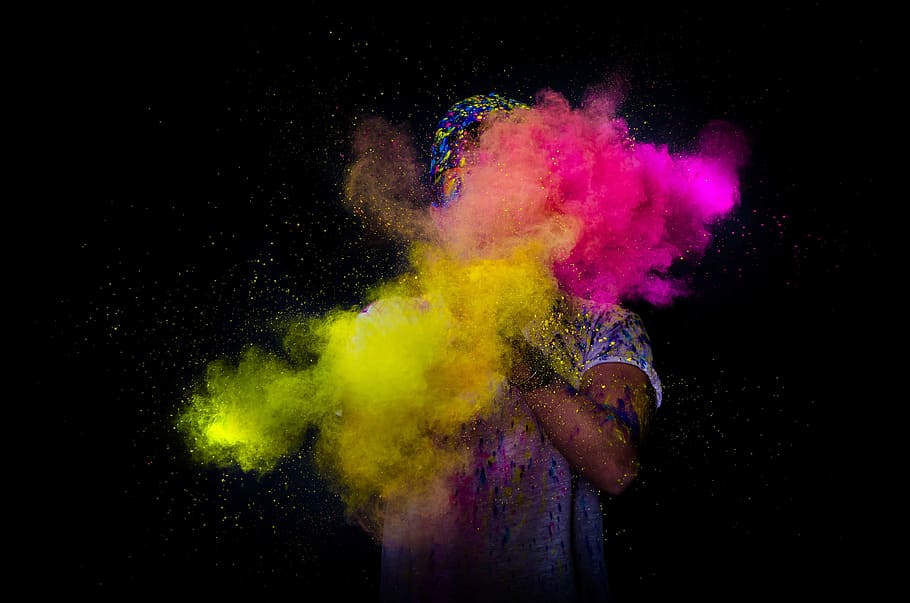 person throwing colored powder, person clapping a colored powders against black background