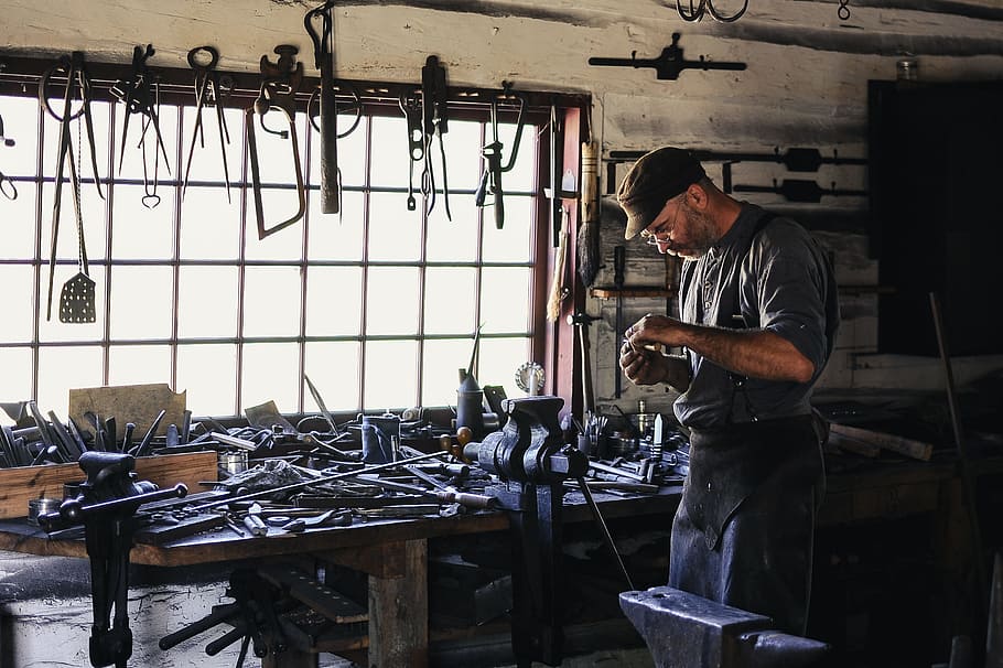 man inside tool shed, man in gray top beside black metal parts