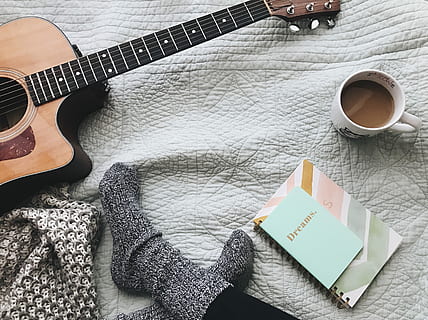 person wearing gray socks near acoustic guitar, person in pair of gray socks sitting in front of acoustic guitar, coffee mug, and spiral notebook HD wallpaper