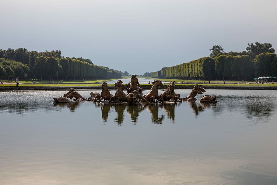 statue of horses on body of water at daytime, statue of team of brown horses on water near trees at daytime