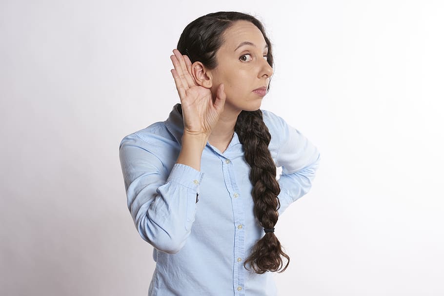 woman putting her right hand near her ear while listening, young