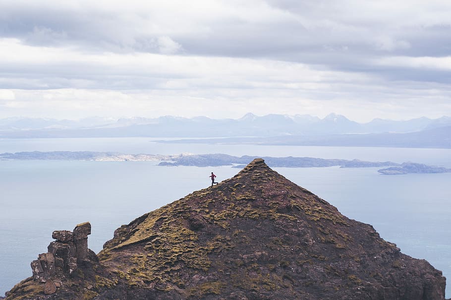 person walking on brown mountain, person standing atop of a mountain during day time