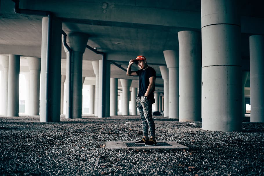 man standing on gray concrete floor, man standing between concrete posts HD wallpaper