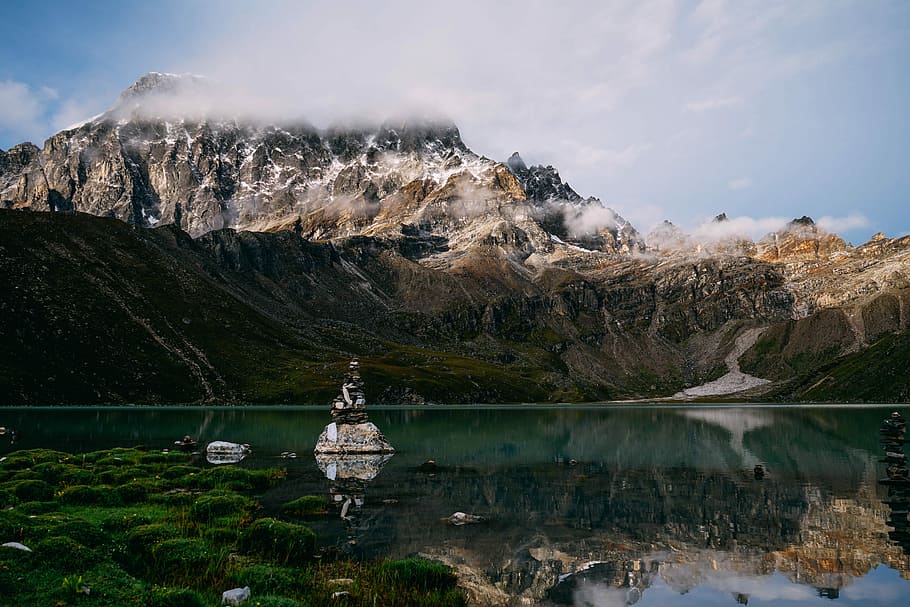 white and gray stone cairn in the middle of body of water near alp mountains, landscape photography of mountain and body of water HD wallpaper
