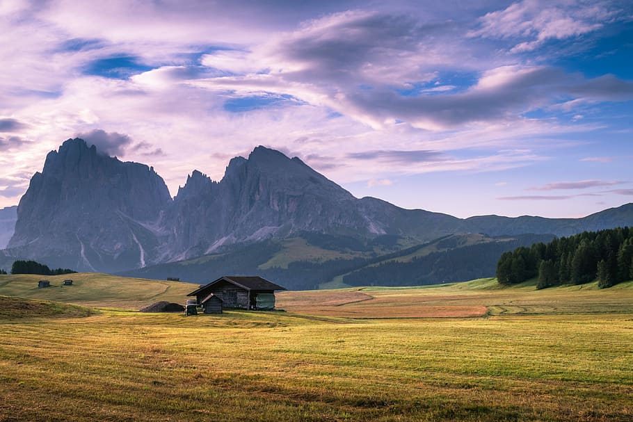 gray wooden house on green plains near mountain range at daytime, landscape photography of shack under nimbus clouds HD wallpaper
