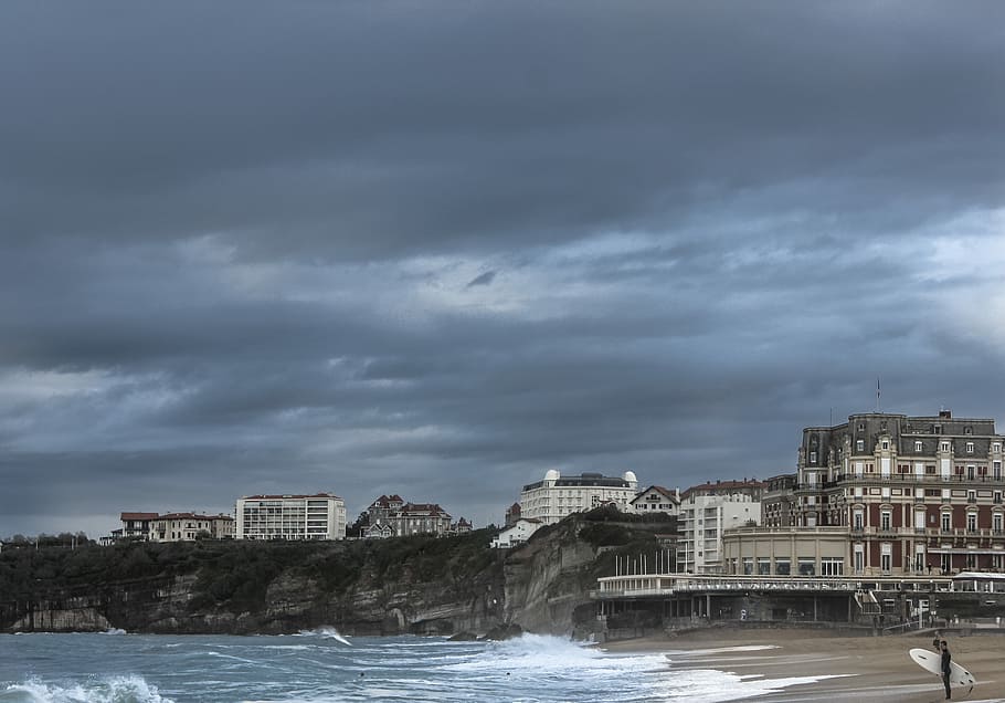 concrete buildings by the sea during daytime, white and grey concrete buildings beside body of water HD wallpaper