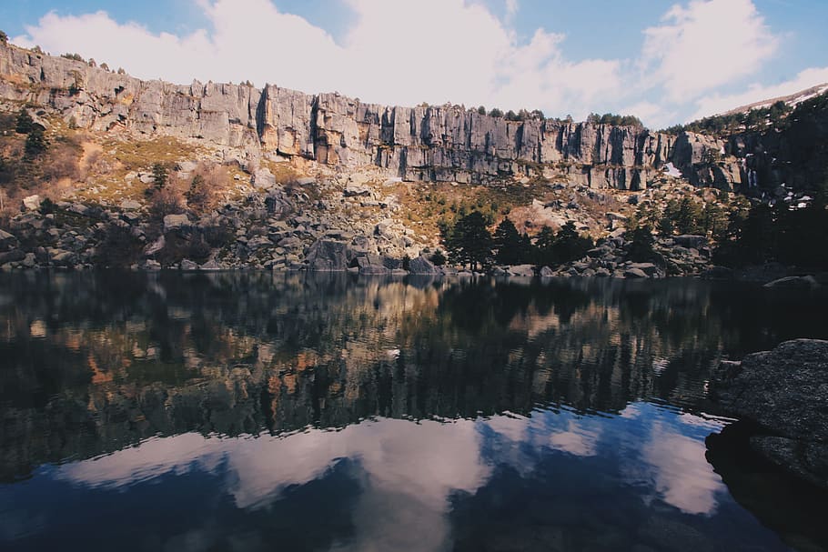 Grey Rocky Mountain Near Body of Water Under Blue Sky With White Clouds during Day Time HD wallpaper