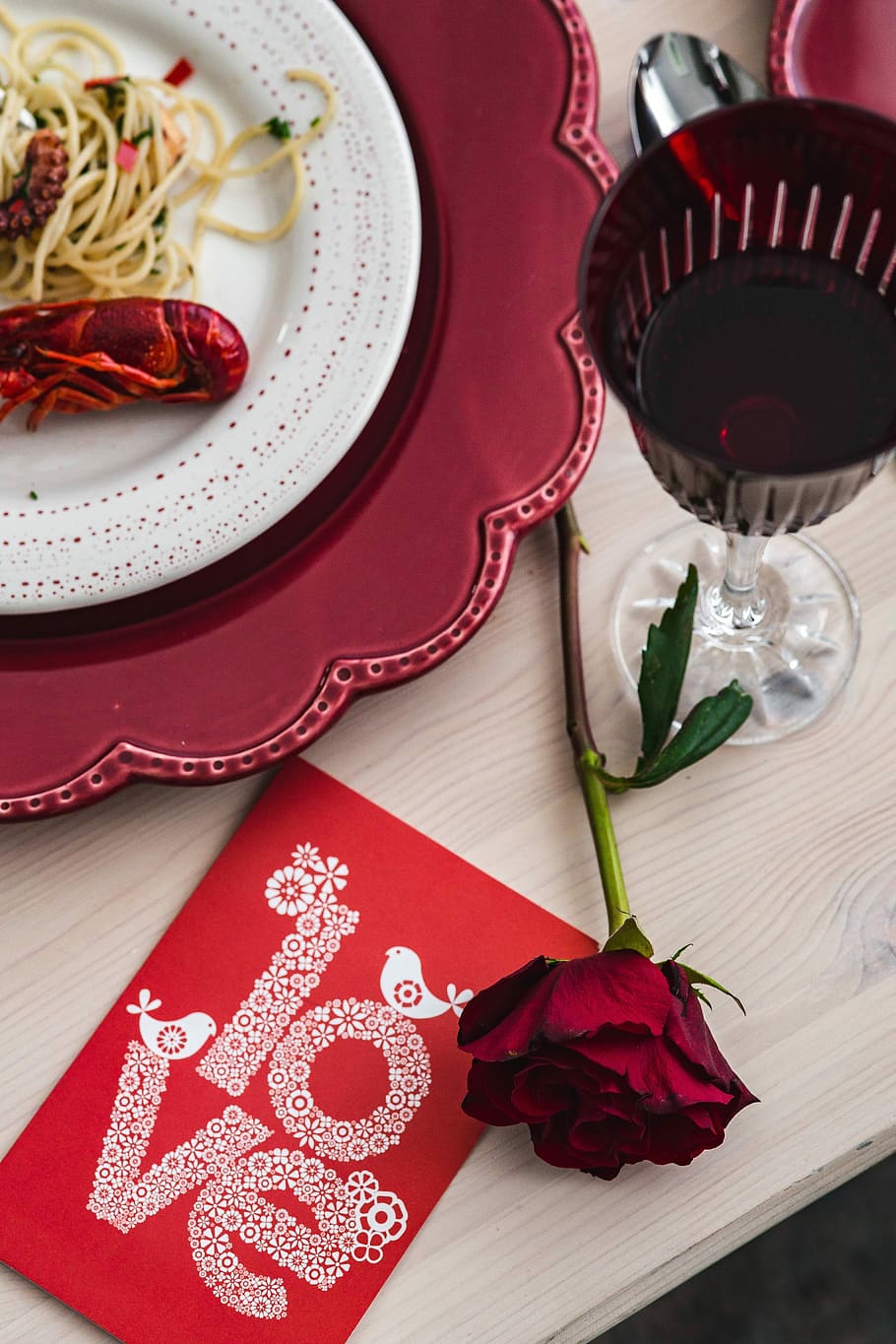 Fancy dinner with seafood pasta, crayfish and red wine by the table decorated with roses HD wallpaper