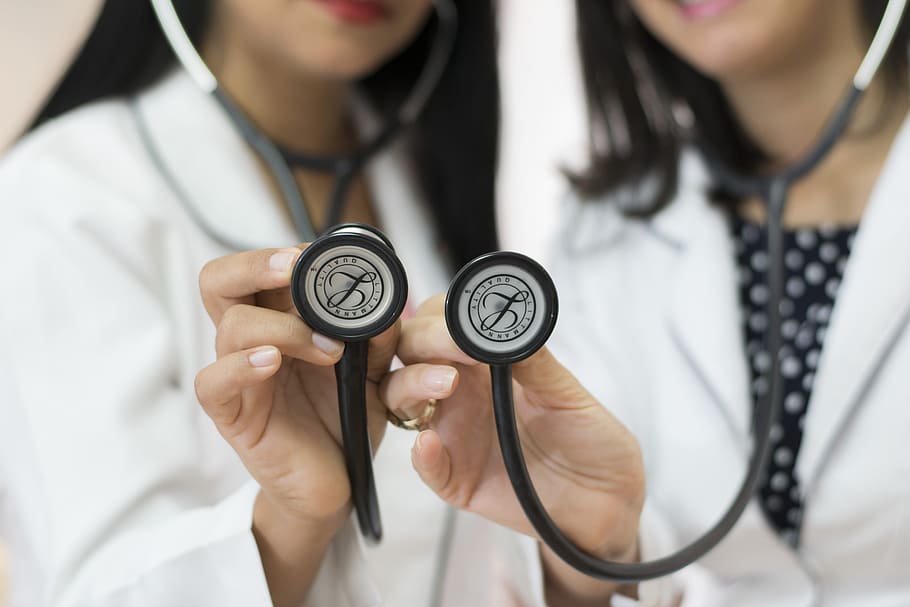 two female doctors holding two black stethoscopes, team, medicine