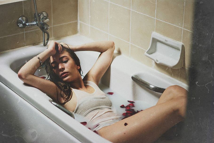 woman lying on bathtub, photo of woman lying on white ceramic bath tub