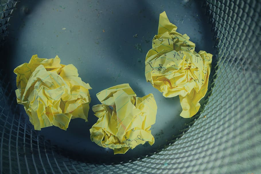 three yellow crumbled papers inside gray trash bin, three crumpled papers