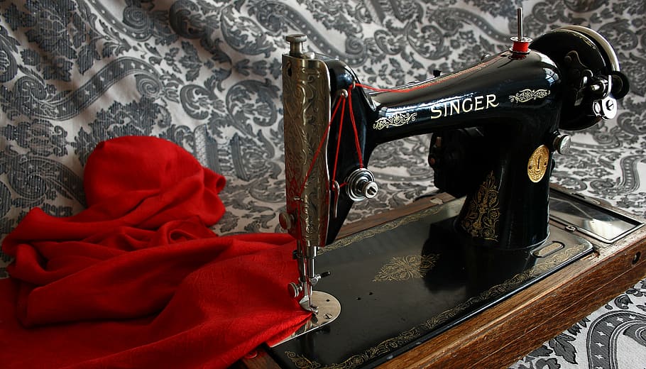 black and brown Singer sewing machine and red textile, antique