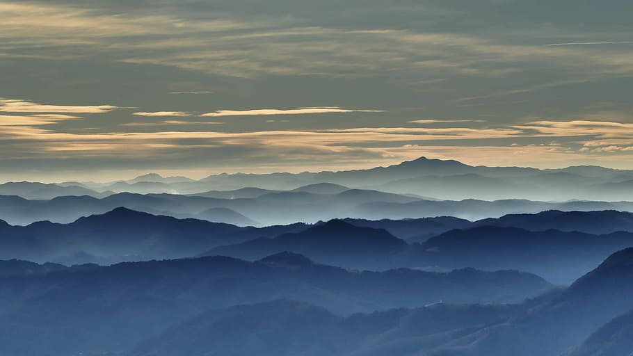 mountains under gray clouds during daytime, aerial view photography of mountains covered by fog under cloudy sky HD wallpaper
