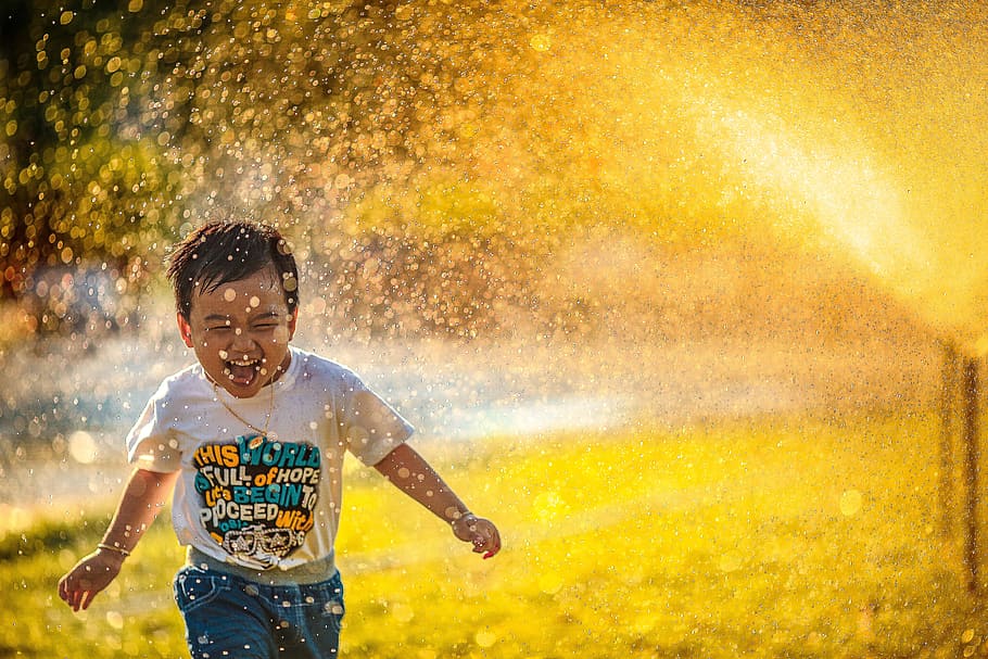 boy playing near outdoor fountain, green grass, child, kid, childhood
