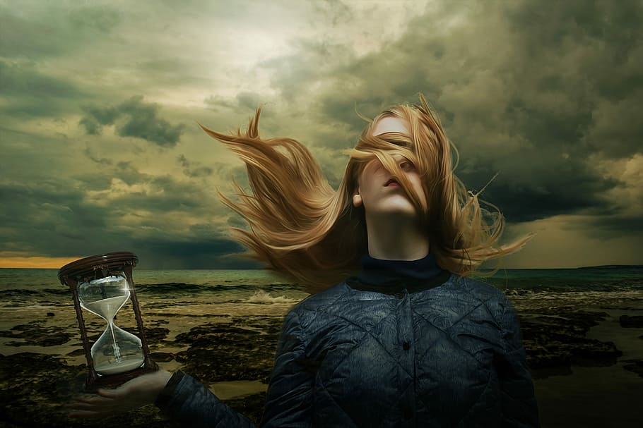 photo of woman holding sand hour glass near seashore under nimbus clouds HD wallpaper