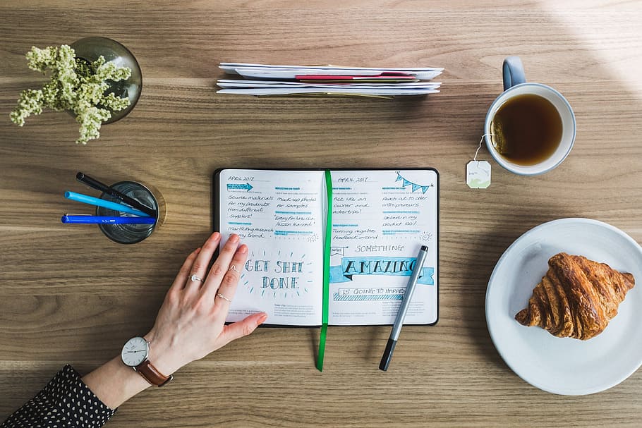 planner in between drinking glass with pens and white ceramic plate with crossaint HD wallpaper