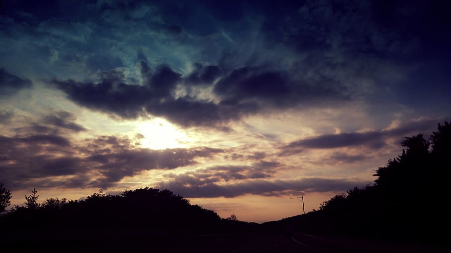 silhouette of mountain under cloudy sky during golden hour HD wallpaper