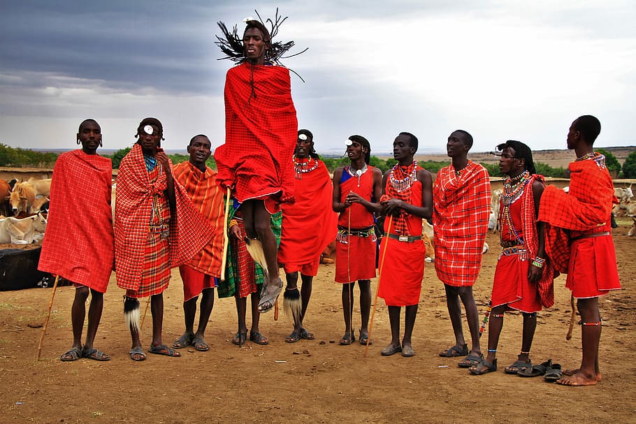 group of men wearing red suits standing on brown soil, man in red robe jumping