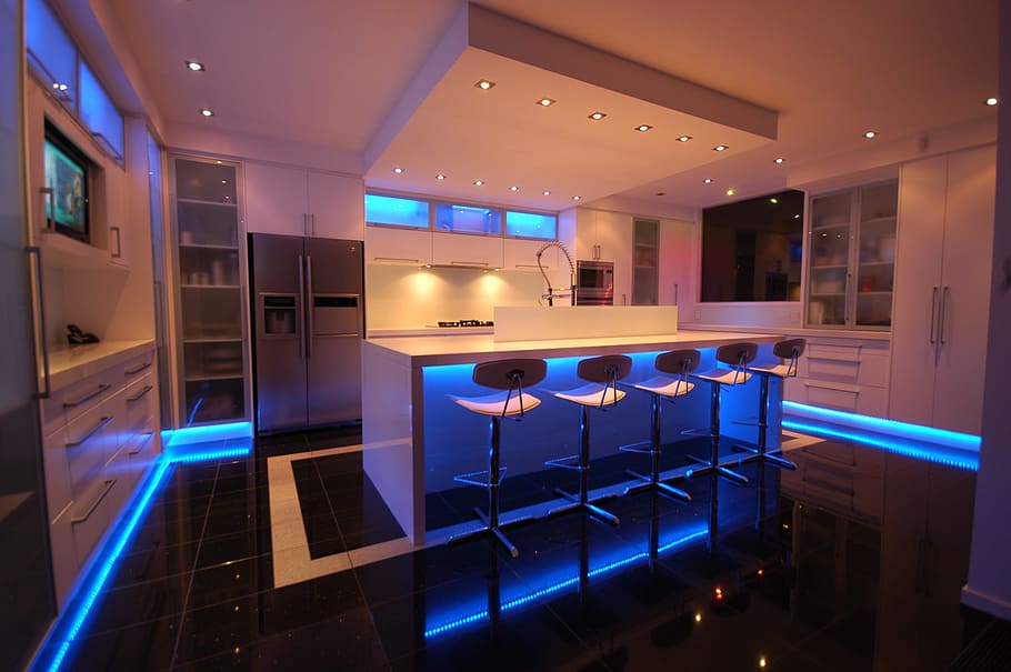 white wooden kitchen with blue LED strips surrounded on corners at night time