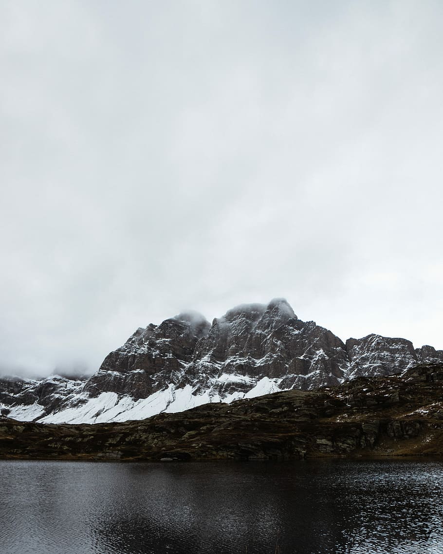 body of water within mountain range during daytime, brown mountain covered by snow near body of water during daytime HD wallpaper