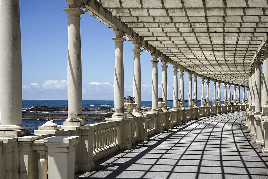 pathway with white columns and roof near blue sea at daytime architectural photography HD wallpaper