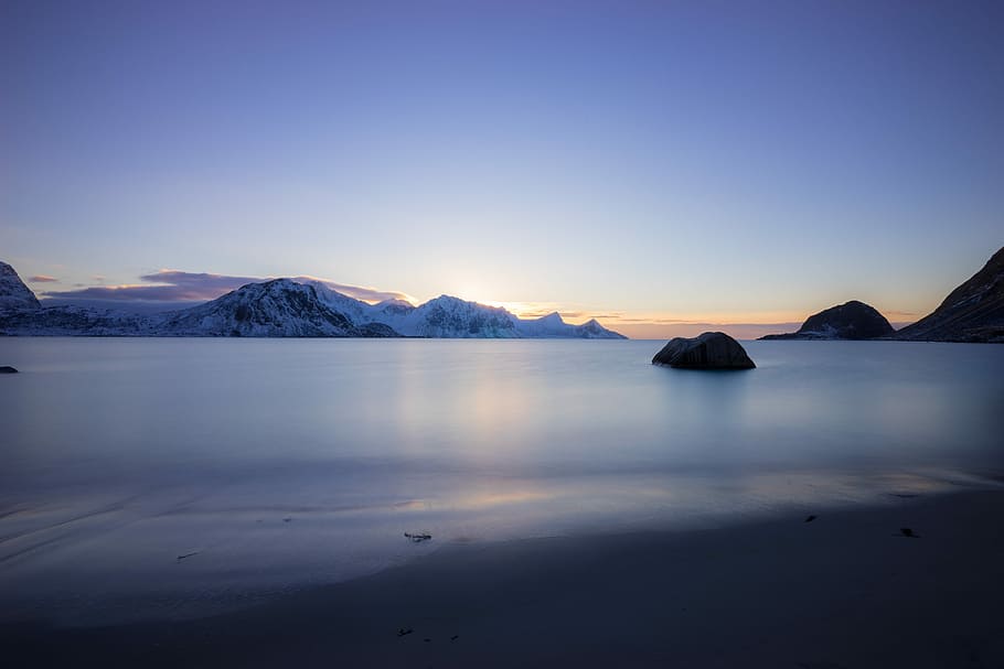 calm body of water near mountain covered with snow, body of water during golden hour HD wallpaper