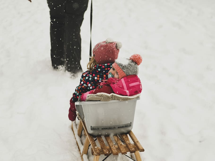 person pulling babies riding on white and brown sled during daytime, two toddler riding on snow sled HD wallpaper