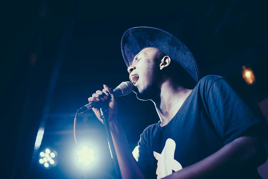low angle of man wearing cap singing in microphone, man holding microphone while singing HD wallpaper