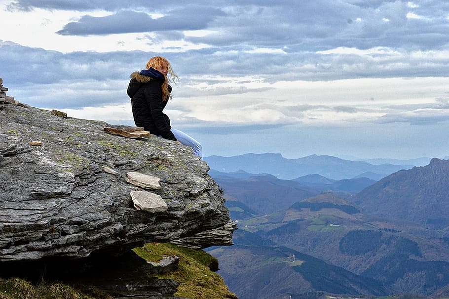 woman wearing parka coat sitting on cliff under blue sky, horizon HD wallpaper
