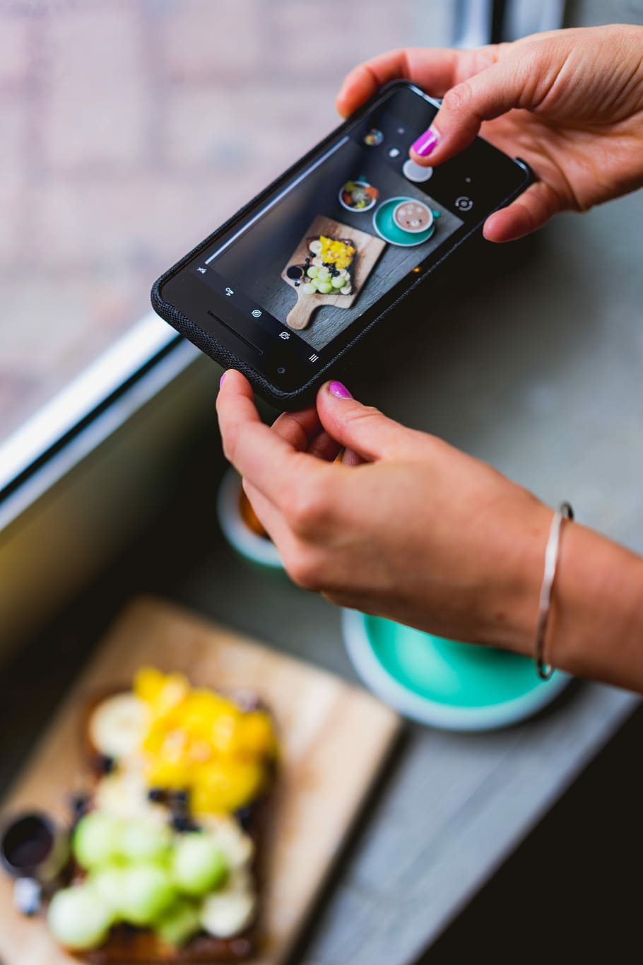 person taking photo of food, close-up photography of person holding black smartphone while capturing sliced vegetables