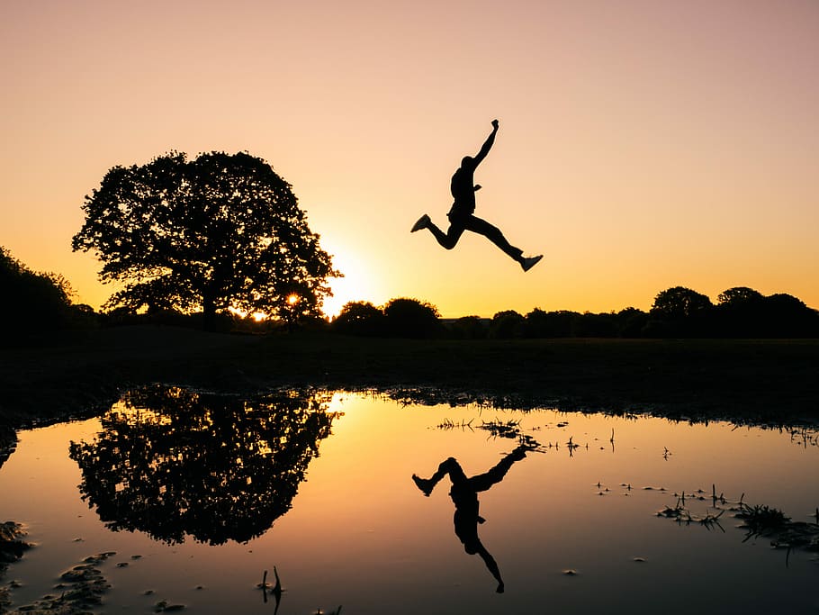 silhouette photo of man jumping on body of water during golden hour, jump shot photo of man silhouette HD wallpaper