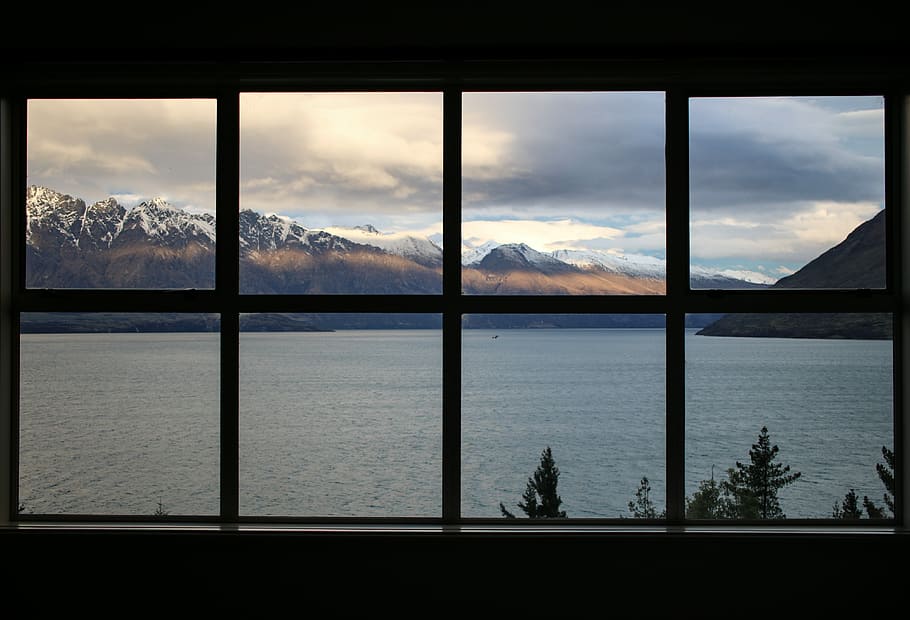 calm body of water near brown mountain under white and gray sky, body of water through window HD wallpaper