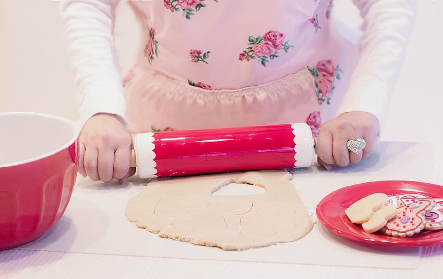 woman holding pink and white rolling pin while baking, valentine