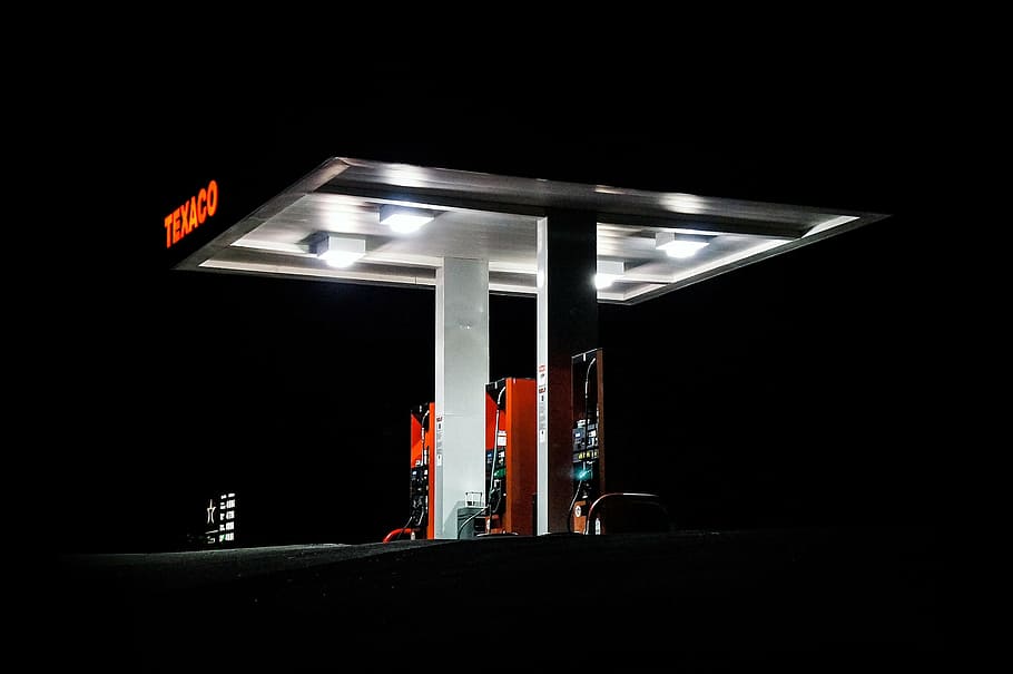 Texaco gasoline station with lights on at night time, silhouette