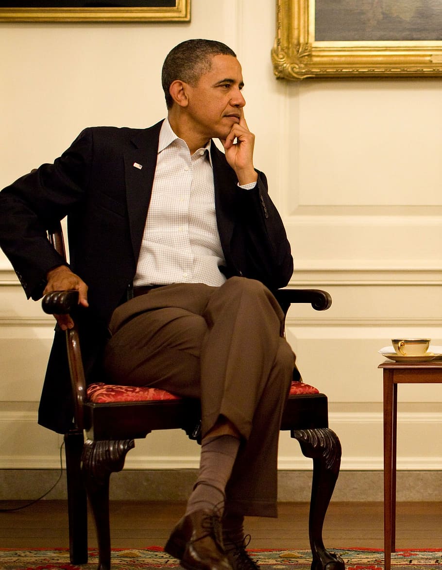 Barack Obama sitting on brown wooden armchair, 2011, thoughtful