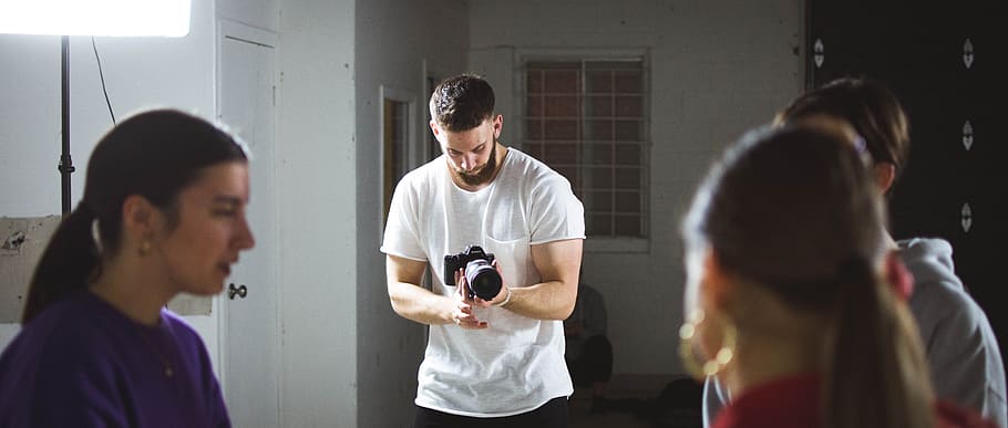 person taking photo of people during daytime, man in white shirt holding DSLR camera HD wallpaper