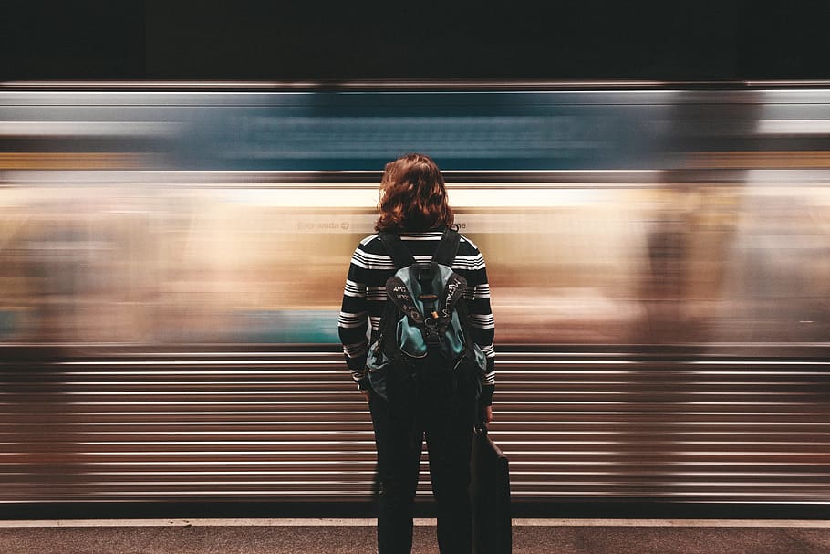 person standing in front of train station, woman standing in front of moving train
