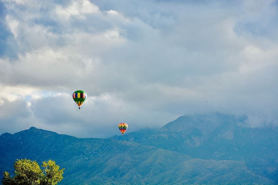 two hot air balloons near mountain, two assorted-color hot air balloons HD wallpaper