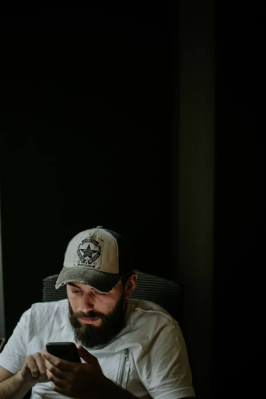 man holding phone, man in gray T-shirt sitting on chair while using smartphone HD wallpaper