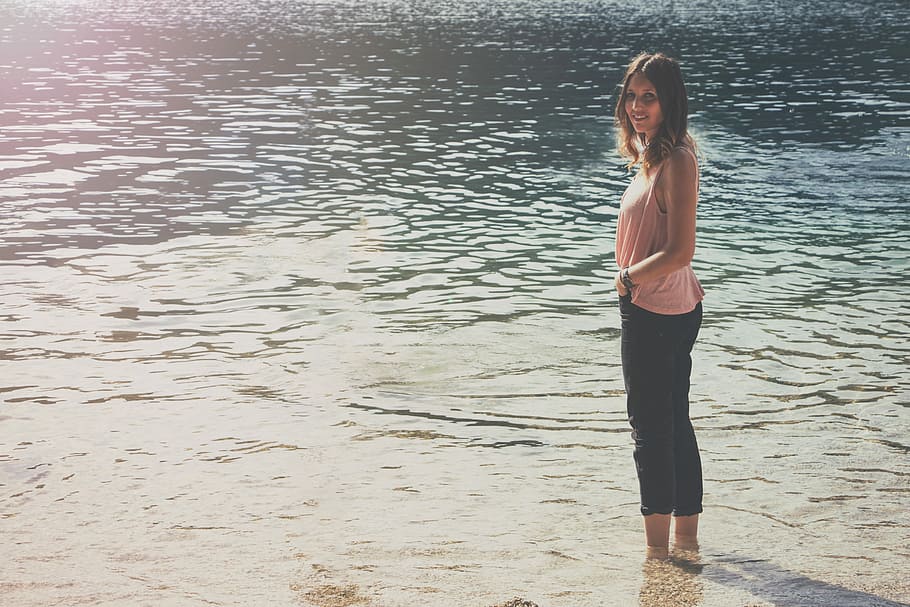 woman in pink sleeveless top and black cargo pants standing on body of water, woman standing in body of water HD wallpaper