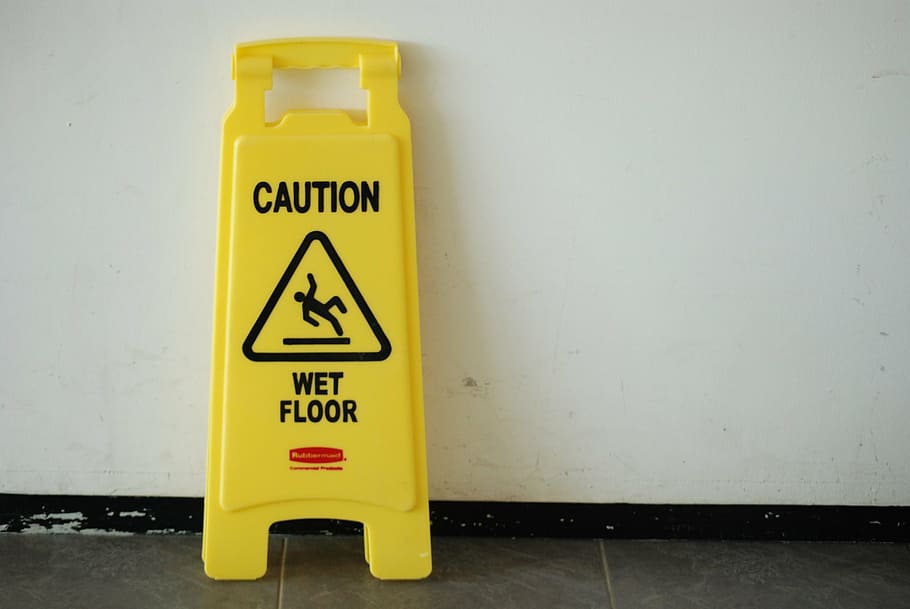 wet floor signage leaning on wall, posted warning, caution, yellow