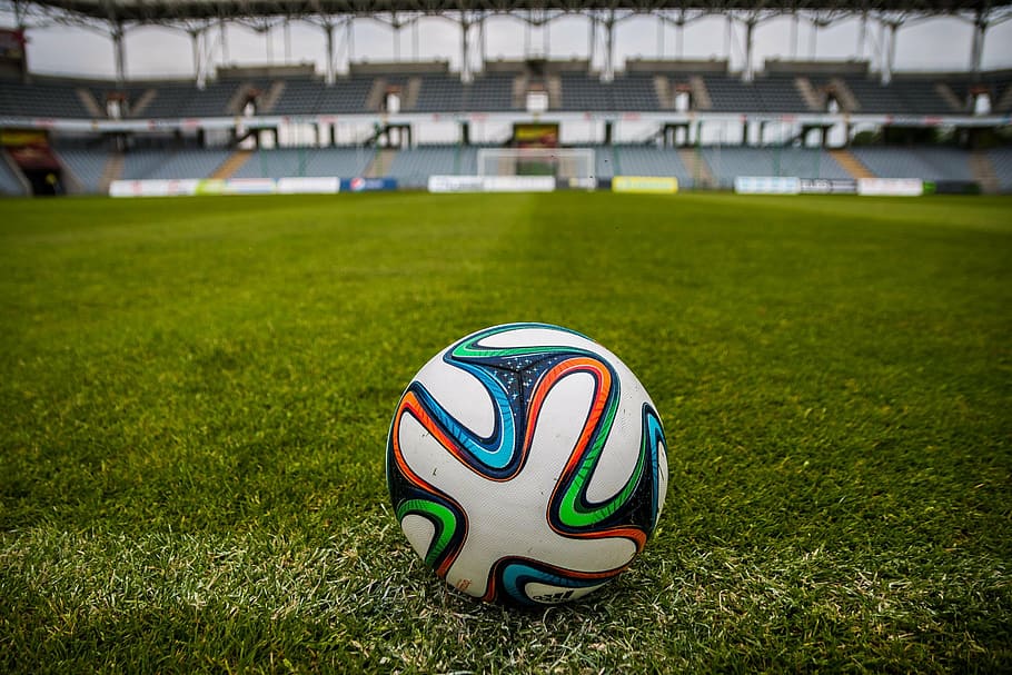 tilt-shift lens photography of multicolored soccer ball on green grass soccer field of an empty stadium