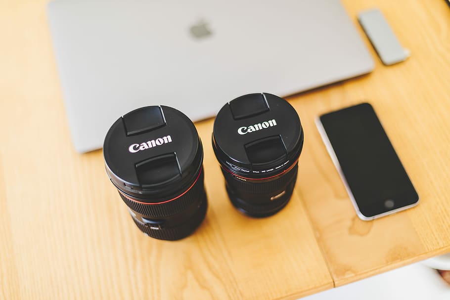 two black Canon camera lens near space gray iPhone 6, black Canon camera lens beside space gray iPhone 6 on brown wooden desk HD wallpaper