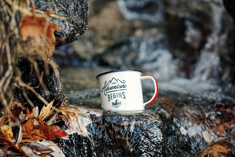 macro shot of white ceramic mug on waterfalls, selective focus photography of mug on rock HD wallpaper