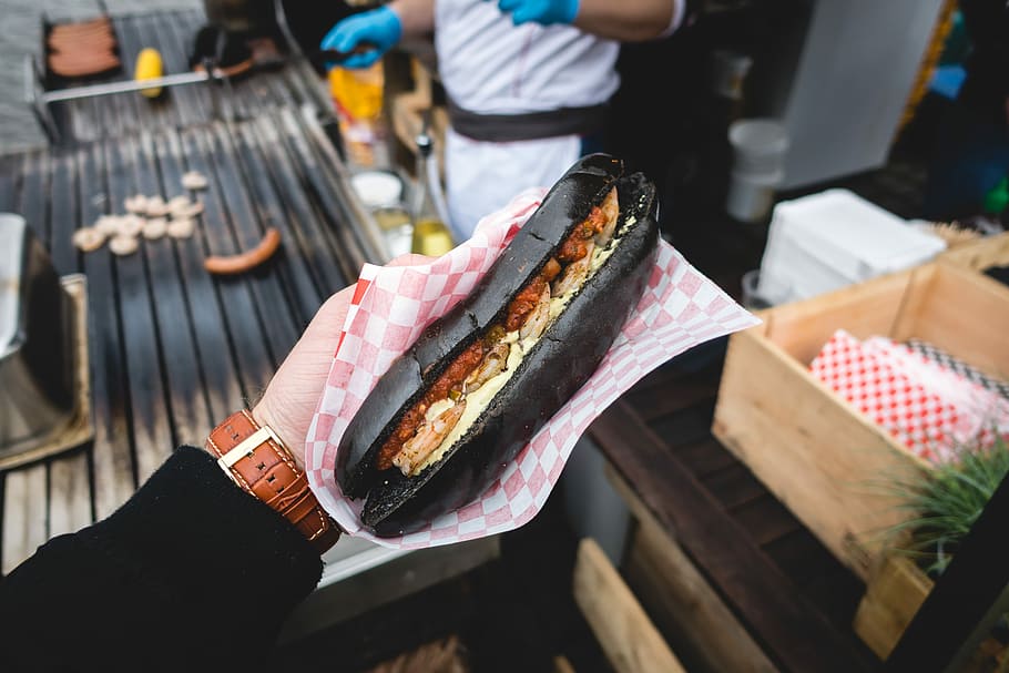 Black squid ink sub with shrimps, hands, outside, sandwich, street food