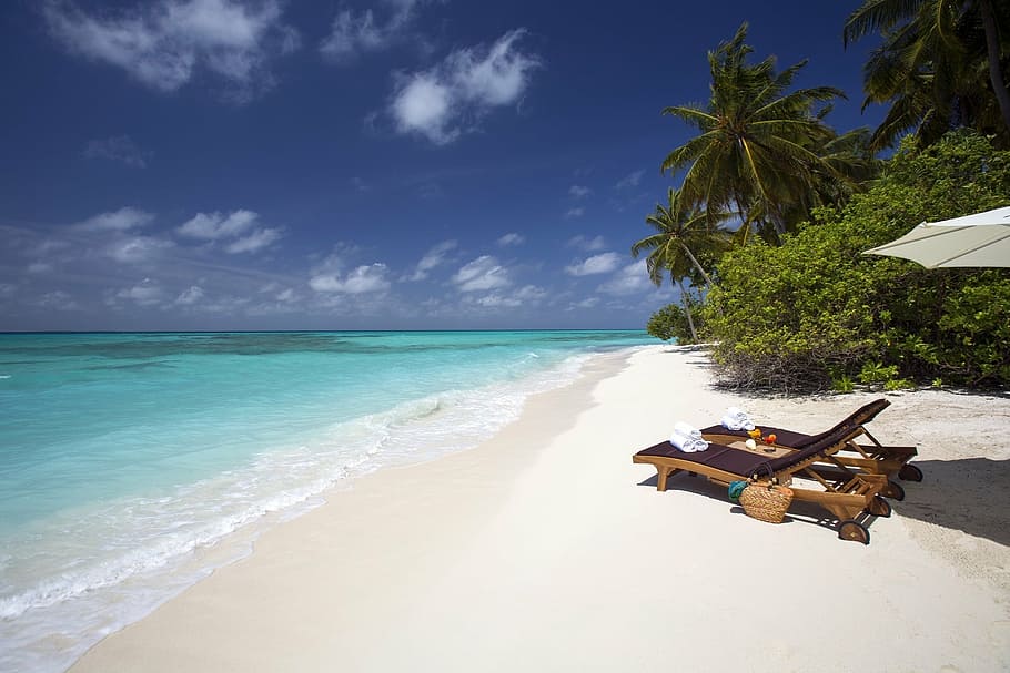 two brown lounger beds near seashore, white sand, beach ocean