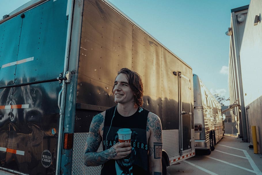 man holding white and red disposable cup, man in black tank top standing in front of black enclosure trailer HD wallpaper